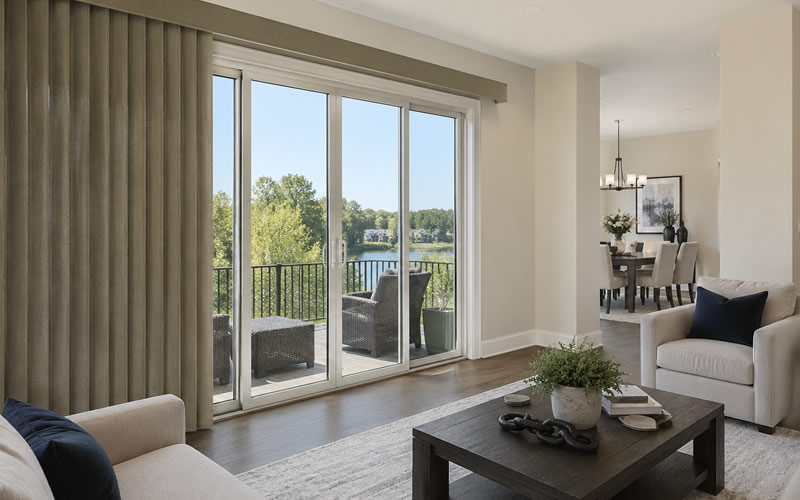 Modern living room with large sliding glass doors and vertical fabric blinds, showcasing natural light control and clean window treatment design for wide openings