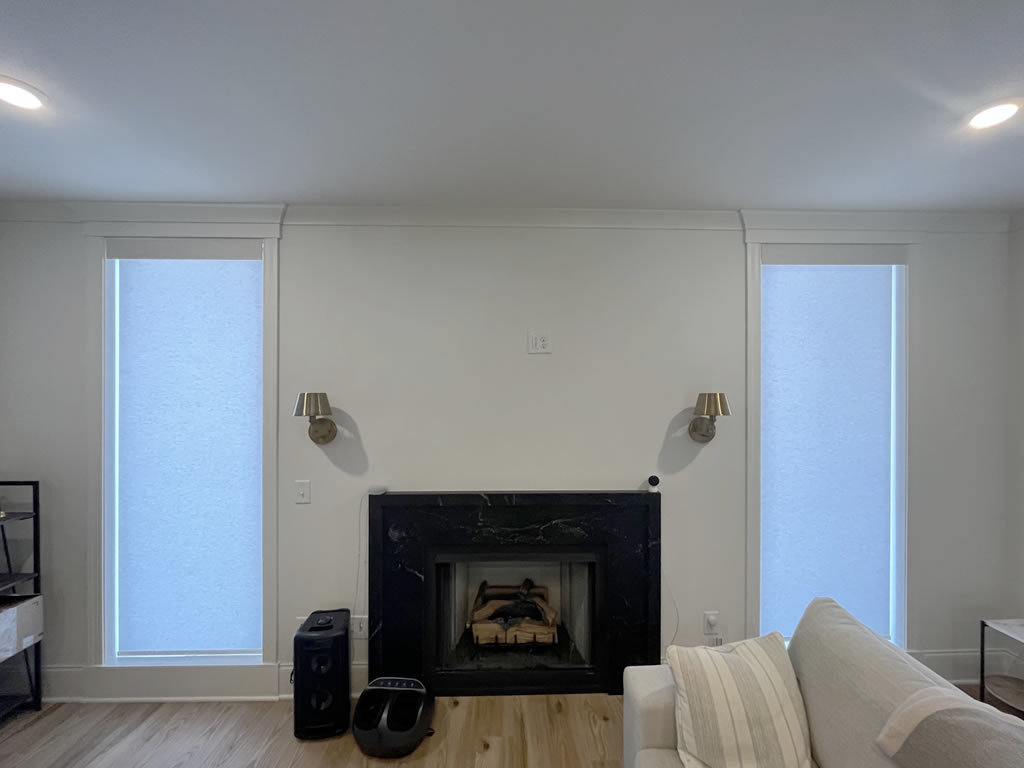 Two roller shades installed around a black fireplace