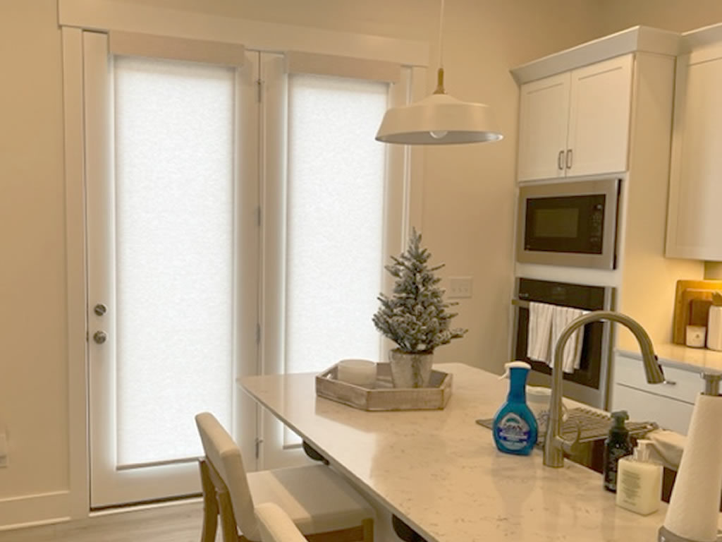 Two roller shades installed on a double-door in a kitchen