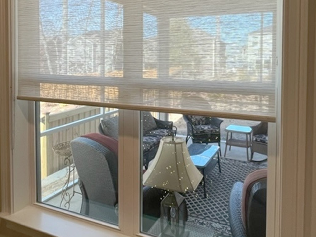 Sheer shads on a window overlooking a front porch where you cna see the porch through the shades and window