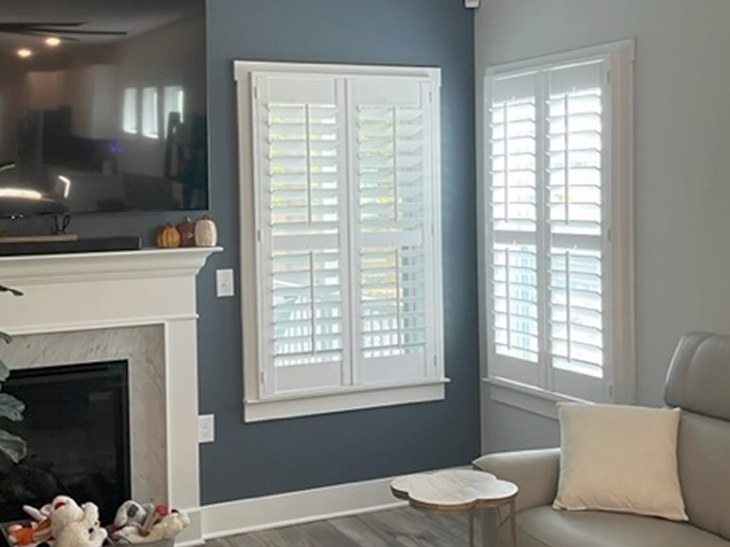 Elegant white shutters installed in a corner of a living room next to a fireplace